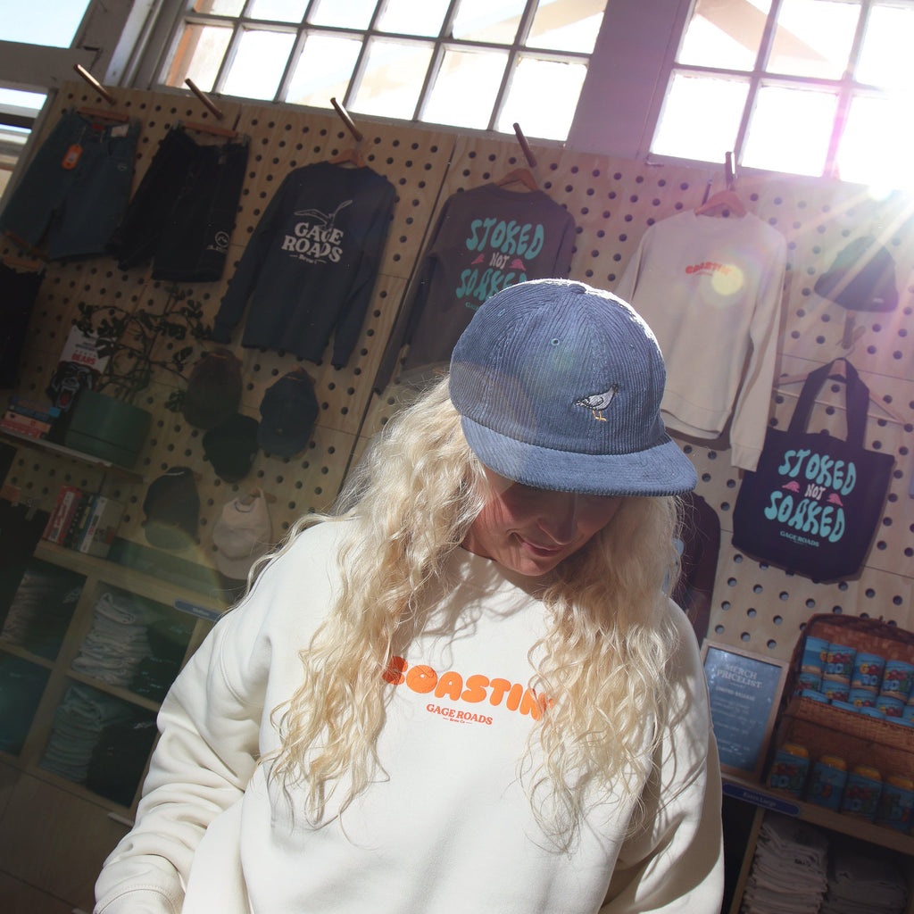 Person wearing a white sweatshirt with orange text in a store setting with merchandise on display.