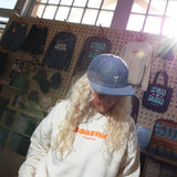 Person wearing a white sweatshirt with orange text in a store setting with merchandise on display.