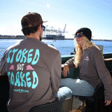Two people sitting on the port with one wearing a shirt that says 'Stoked Not Soaked'.